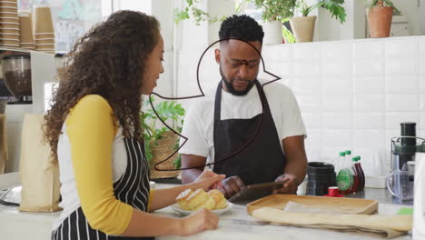 two people in aprons discussing over tablet in kitchen with red animation