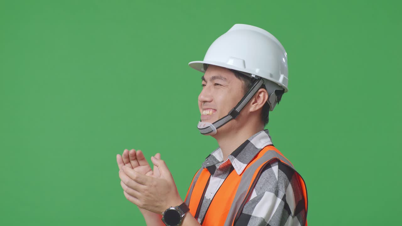 Close Up Side View Of Asian Male Engineer With Safety Helmet Smiling And Clapping His Hands While Standing In The Green Screen Background Studio