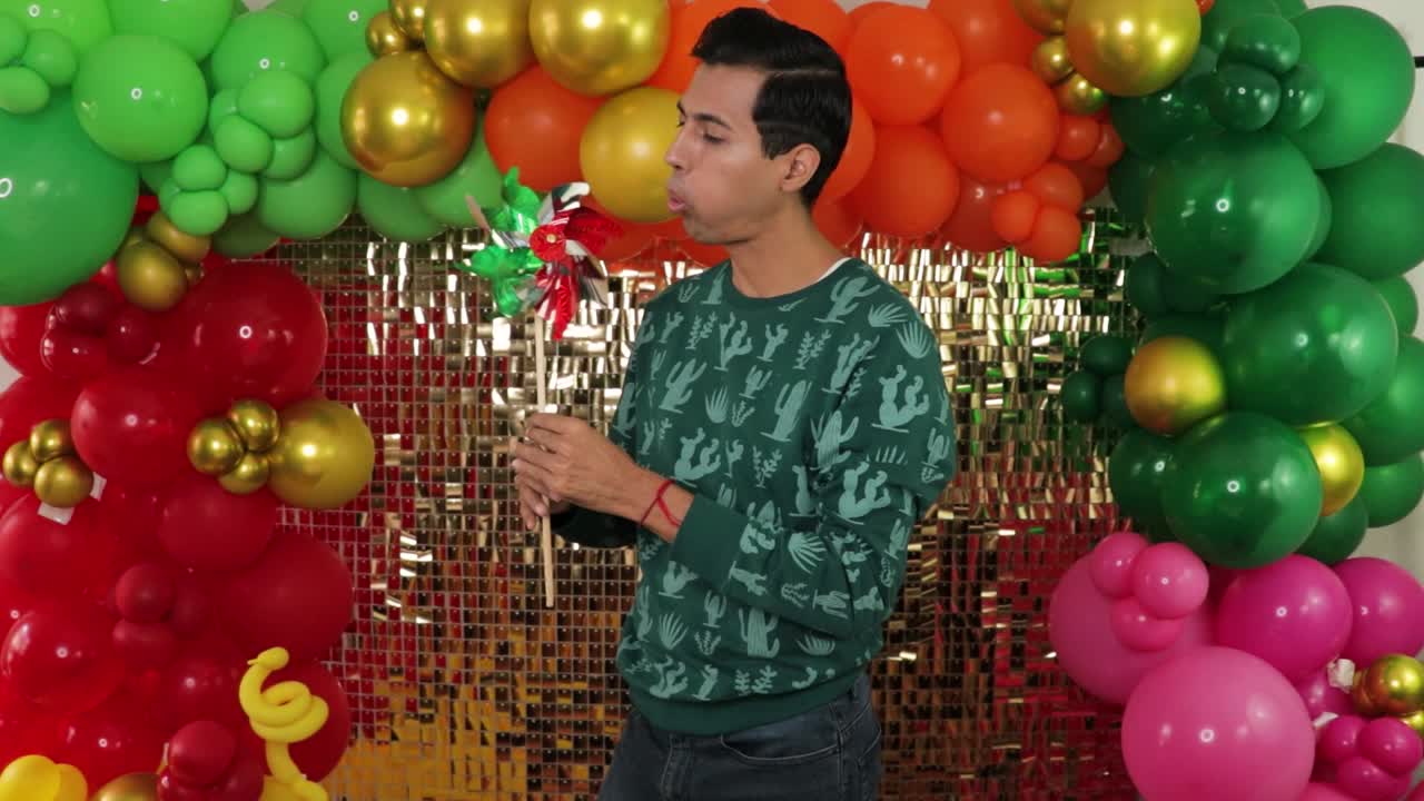 joven mexicano celebrando, girando molino de viento tradicional con telón de fondo festivo