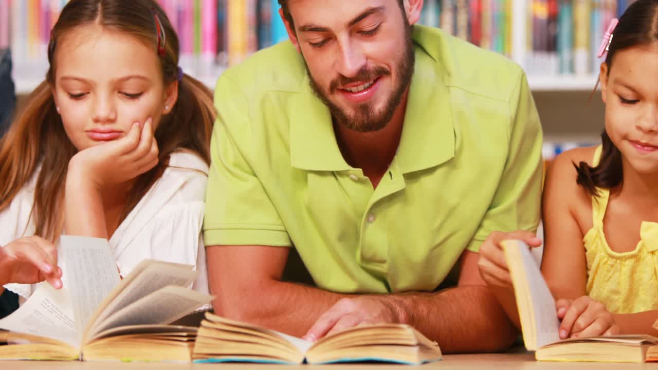 maestro y niños leyendo un libro en la biblioteca
