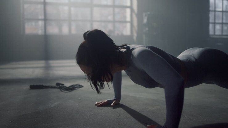 Woman standing in plank. Athletic girl doing push ups in sport club