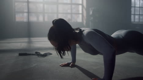 woman standing in plank. athletic girl doing push ups in sport club