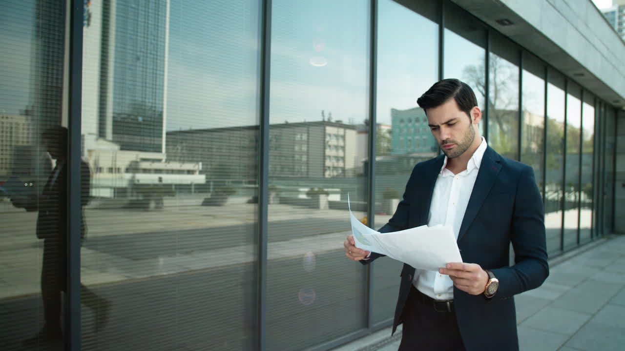 Serious businessman reading documents outdoors