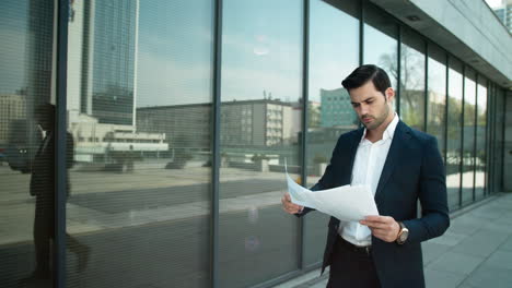 hombre de negocios serio leyendo documentos al aire libre