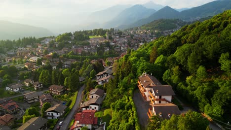 panoramic drone view of selvino with treetops, buildings, and distant alpine ridges wrapped in evening mist. shot at selvino, italy (selvino, italia)