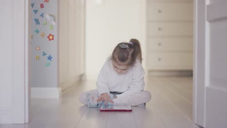 niña jugando tablet en el suelo en casa