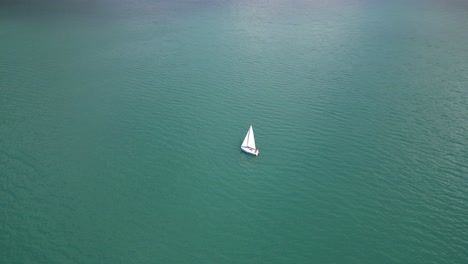 Yate-Blanco-Navegando-Tranquilamente-En-El-Vasto-Lago-De-Suiza,-Vista-Aérea