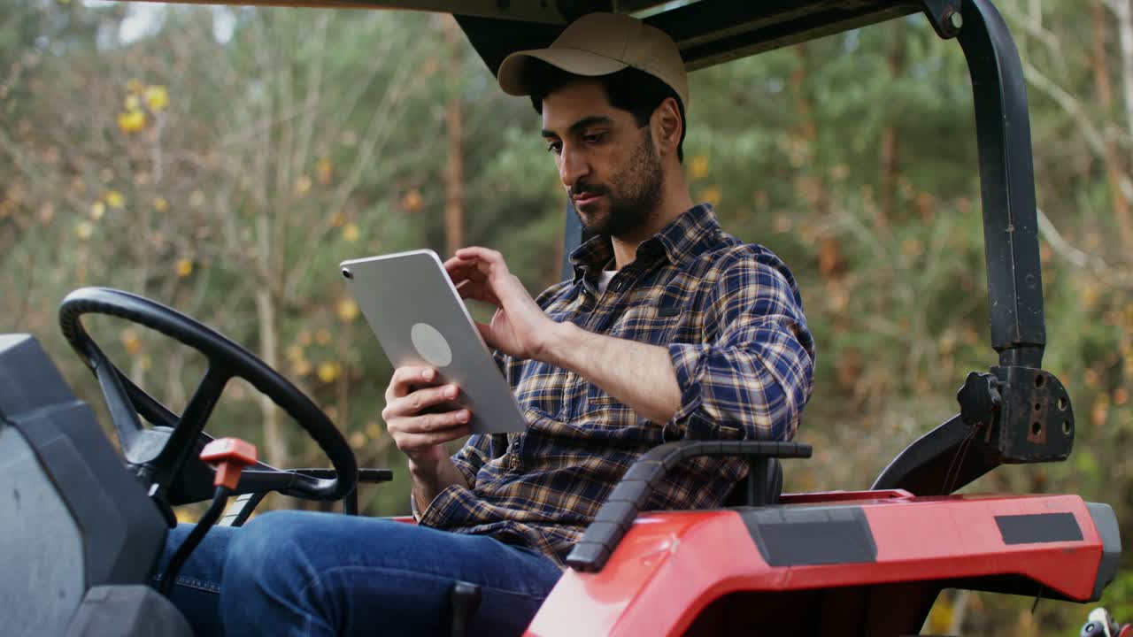 agricultor que utiliza una tableta digital en el tractor