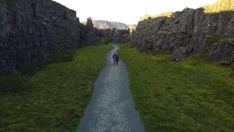 Aerial-drone-shot-of-couple-walking-in-the-street-in-between-the-mountains