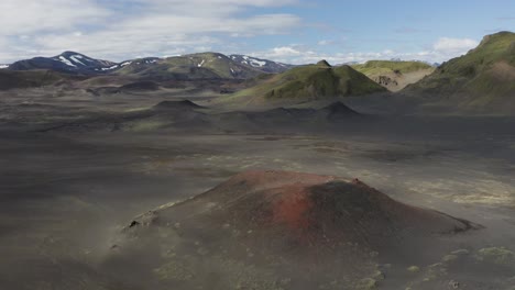 Luftaufnahme-Des-Roten-Kratervulkans-Und-Des-Schneebedeckten-Berggipfels-Im-Hintergrund,-Island