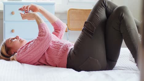 침대 4k에 휴대 전화를 사용하는 아름다운 여성