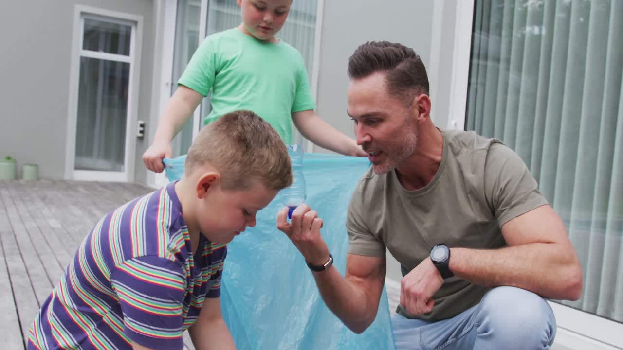 백인 아버지 와 두 아들 이 야외 에 있는 가방 에 플라스틱 재료 를 넣고 있다