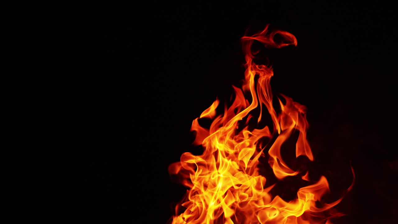 Fire flames, smoke and tiny sparks flying up. Burning bonfire at dark night. Close up.