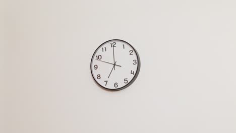 a wide 4k shot of a classic black and white wall clock on a plain white wall, displaying the time as x:00.