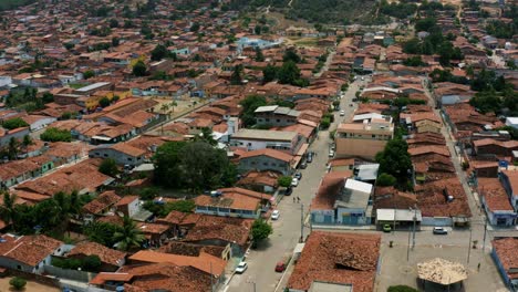 Dolly-in-aerial-drone-shot-of-a-small-rural-residential-street-in-the-tropical-beach-town-of-Baia-Formosa-in-the-state-of-Rio-Grande-do-Norte,-Brazil-with-colorful-neighborhoods-and-green-foliage