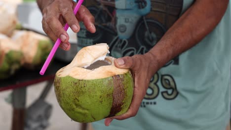 una persona cortando y sirviendo un coco.