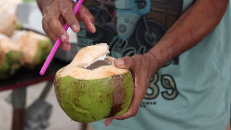 person slicing open and serving a coconut.