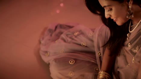 a smiling lady drawing an art created on the floor using flower petals, colored sand and oil lamps