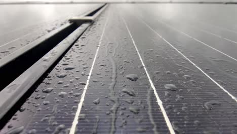 rain dripping gently on solar panel with silicon solar cells and drops flow gently downwards on panel - closeup of wet solar panel with silicon circuits