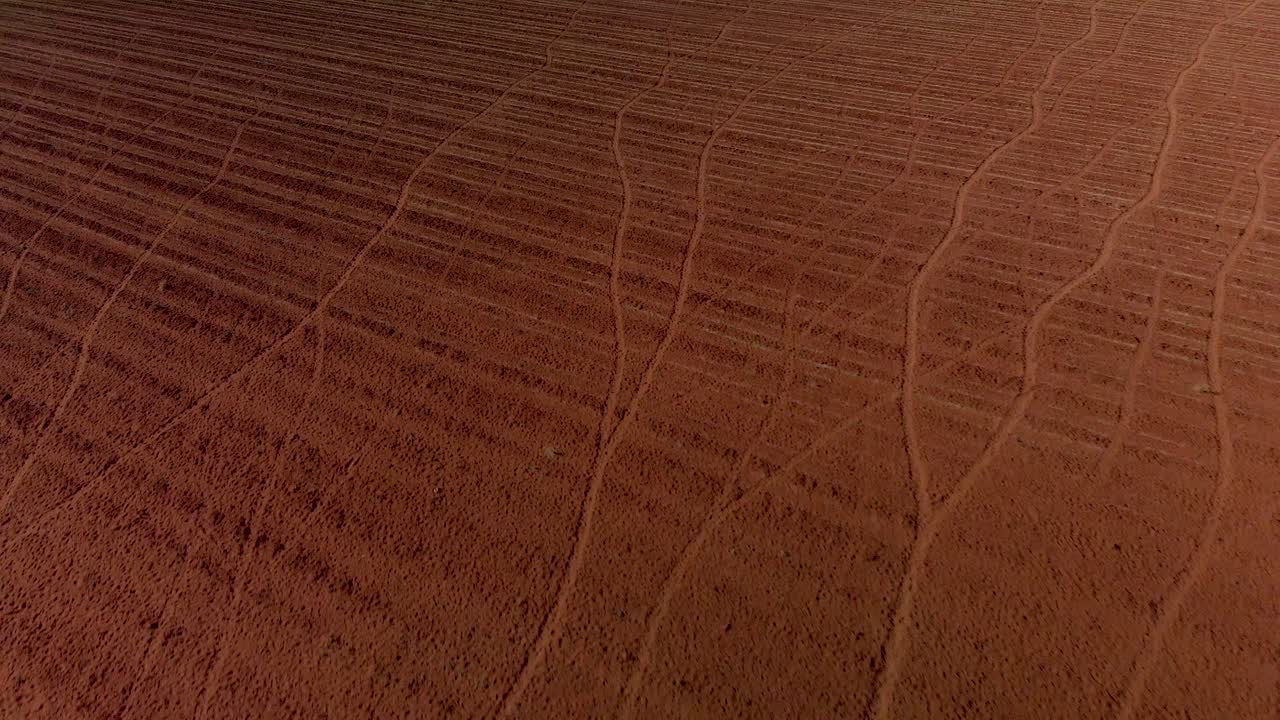 dolly inverso aéreo que revela una bomba de viento en funcionamiento en una granja con tierra arada sin usar