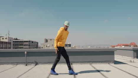 dancing-man-hip-hop-dancer-performing-freestyle-dance-moves-on-rooftop-in-city-wearing-yellow-hoodie