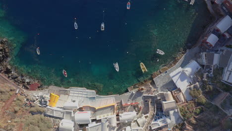 antena: toma de arriba hacia abajo de la bahía de ammoudi en oia de santorini con muchos botes pequeños