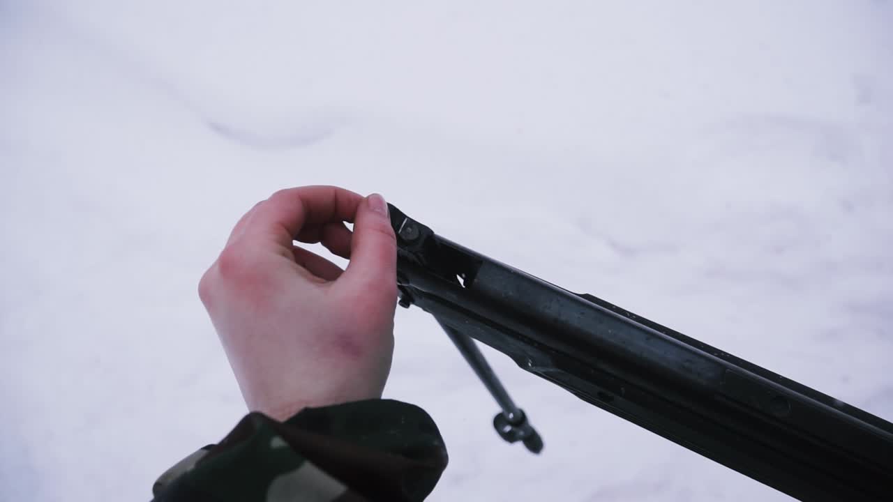 Person Holding and Adjusting a Hunting Rifle in the Snow