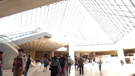 people walking inside louvre museum's glass pyramid