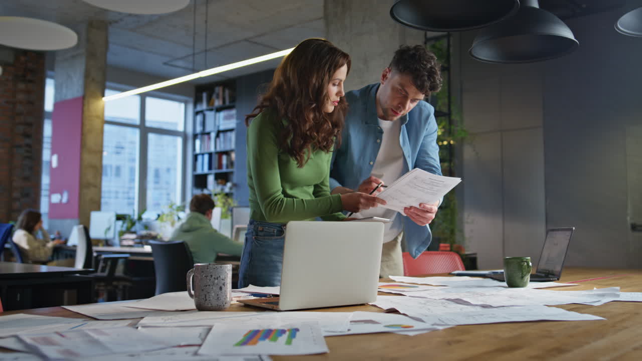 Two colleagues looking documents in modern office closeup. Man woman working