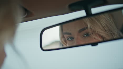 girl looking automobile mirror enjoying beauty close up. blonde checking makeup.