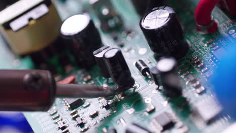 Close-up-of-a-technician-soldering-a-capacitor-to-a-circuit-board-with-a-wisp-of-smoky-fumes-coming-out-of-it
