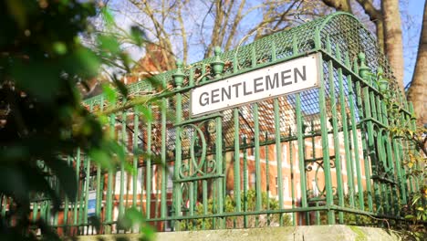 an old "gentlemen" sign on vintage public toilets under sunny skies, nostalgic design and outdated gendered restrooms