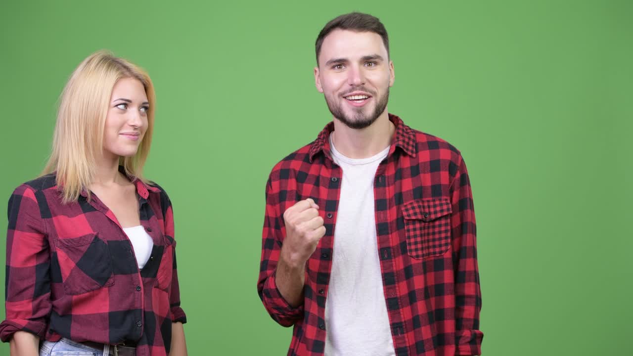 Young woman whispering to young man and looking excited