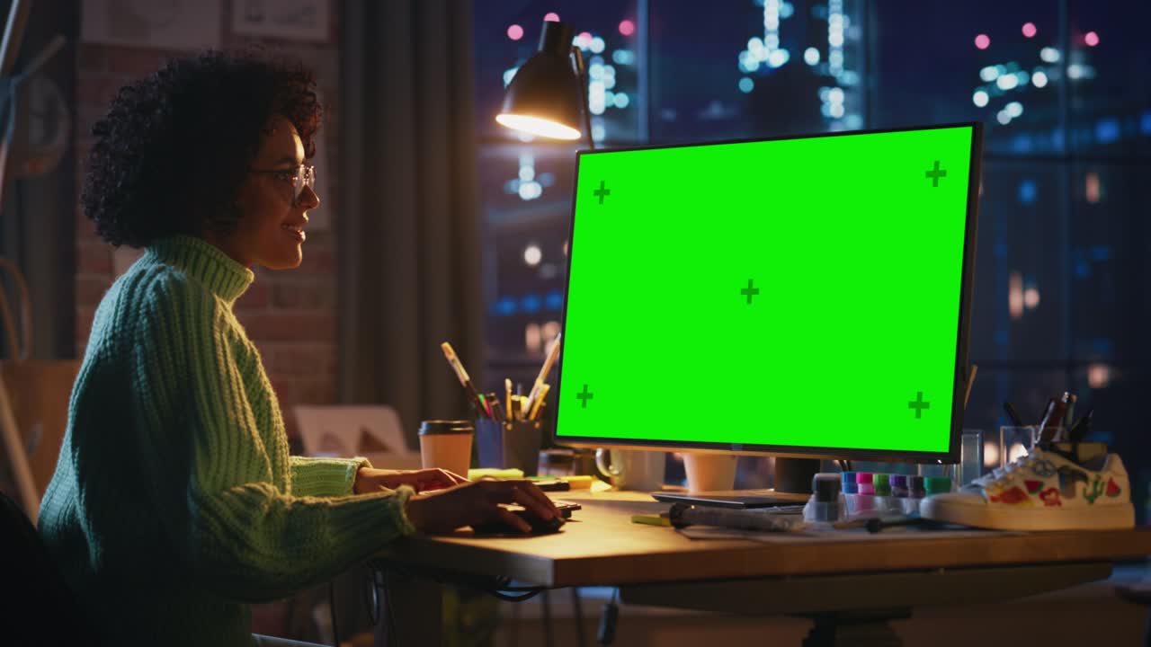 empleada creativa negra trabaja en su computadora personal con una gran pantalla verde en un espacio de loft fresco. chica positiva satisfecha de los resultados. concepto de estudio y ocupación