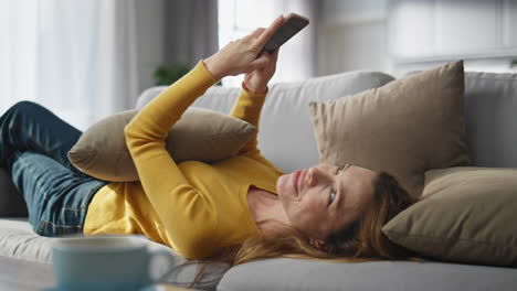 chilling lady messaging mobile phone laying sofa closeup. woman typing message