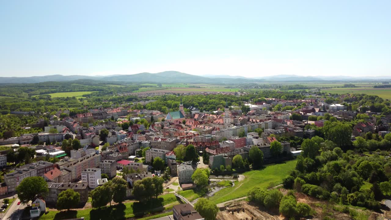 edificios históricos de la ciudad y el campo exuberante, enmarcado por colinas distantes bajo un cielo azul claro