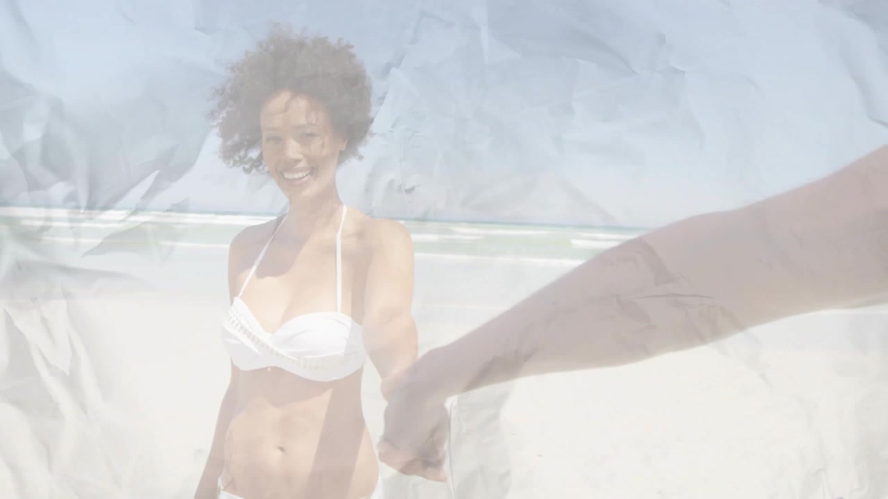 Il braccio del partner che si allunga, una donna in bikini bianco che tiene la mano, sorridendo e camminando sulla spiaggia per un viaggio