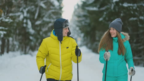 un hombre con una chaqueta amarilla y una mujer con un mono azul en el invierno en el bosque esquiando en cámara lenta