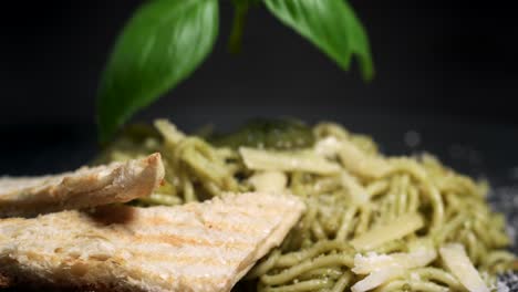 Spaghetti-with-green-pesto,-parmesan-and-bread-are-garnished-with-basil