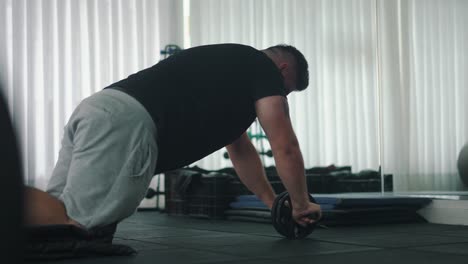 Strong-Young-Man-Doing-Abs-Roll-out-Exercise-in-the-Gym