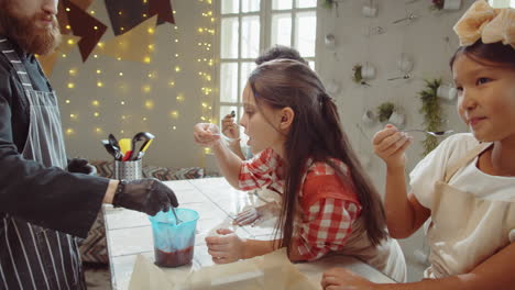 los niños intentan salsa durante la clase culinaria con el chef
