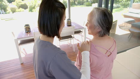 assisting senior asian woman with shoulder exercise, physiotherapist working at home