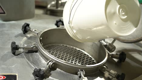 fishery industry: a worker pouring fish processing additives from a bucket into a machine, slow motion handheld shot