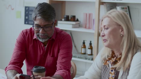 senior colleagues discussing data on smartphone screen in office
