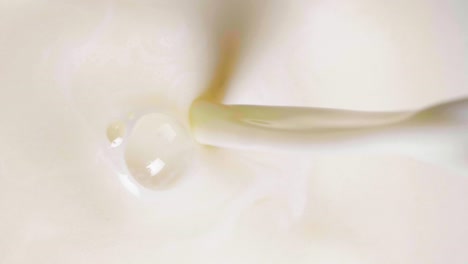 toma vertical de primer plano de leche de avena vegana vertida en un vaso en cámara lenta