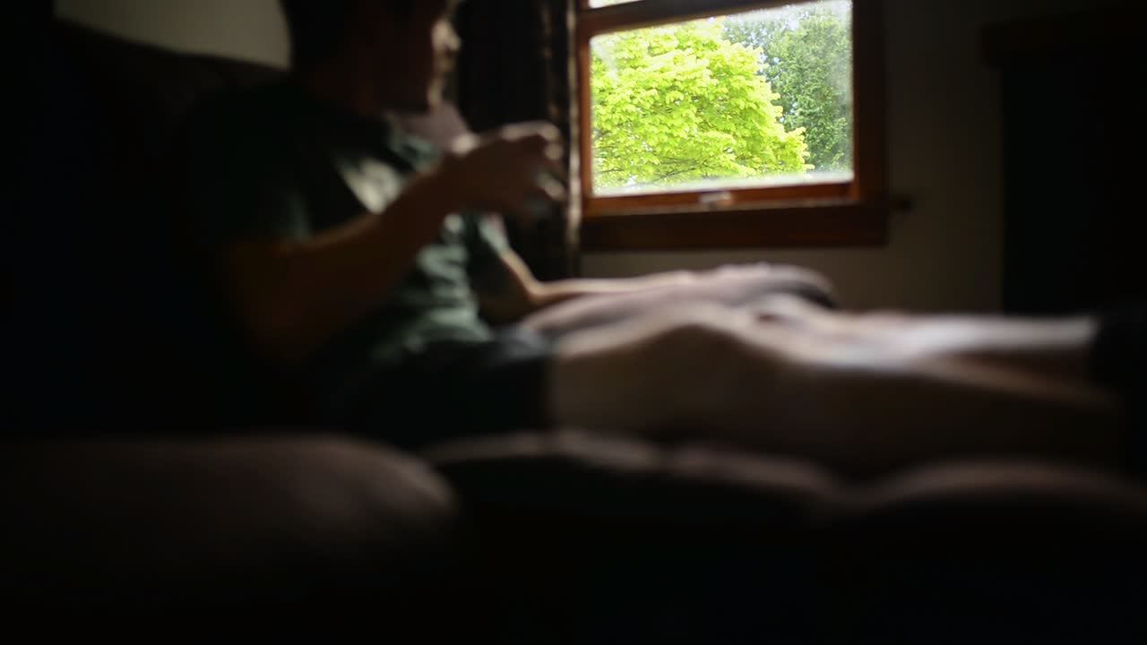 접는 소파에 앉아 커피를 마시며 정원을 마주한 창 밖을 내다보는 남자