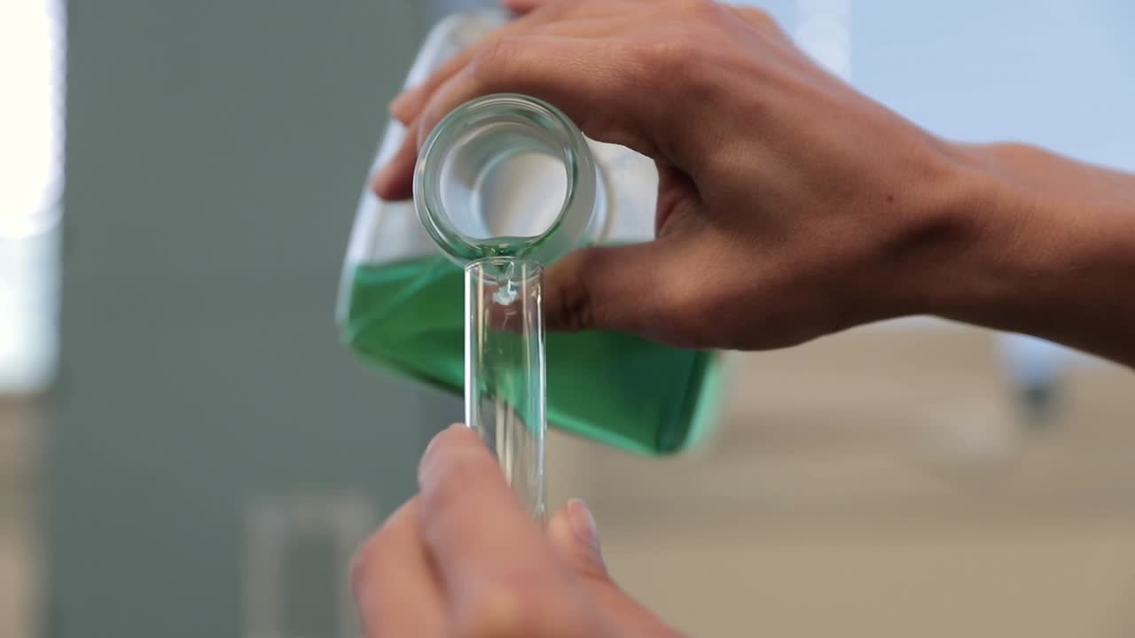 Scientist Pouring Green Liquid into Test Tube in a Laboratory