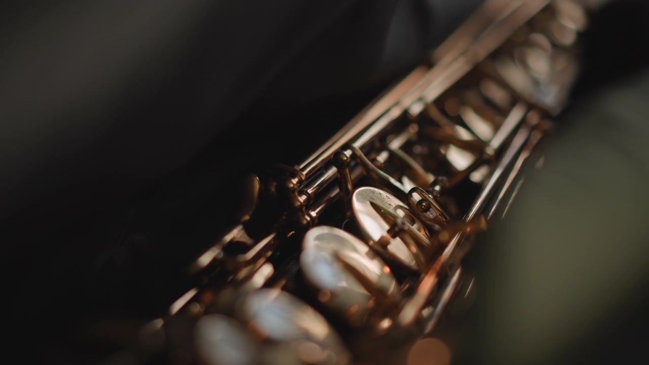 Lowangle saxophone keys during warmup, technician or roadie prepping instrument before gig, dark moody backdrop with spotlight glint, brass lacquer and pearl pads in crisp focus, cinematic shallow