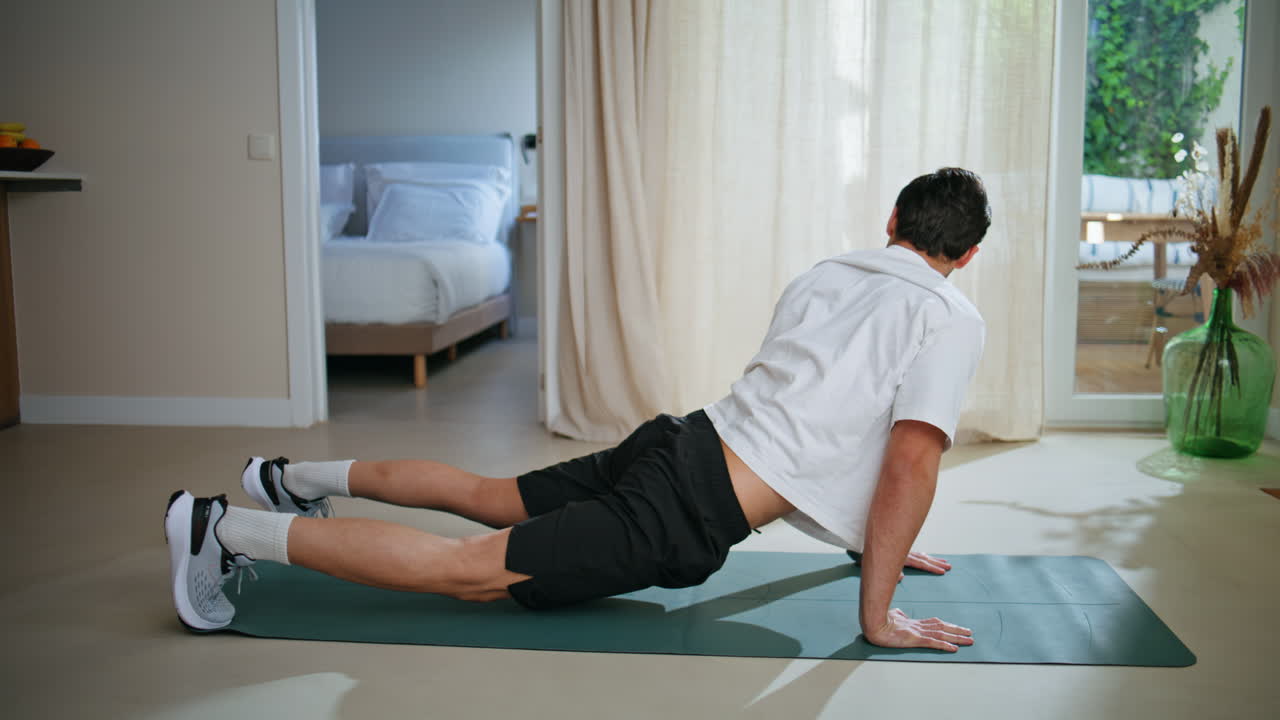 Handsome athlete stretching body practicing upward dog yoga pose on mat