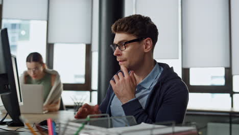 Computer-guy-looking-screen-on-office.-Thoughtful-engineer-checking-code-problem